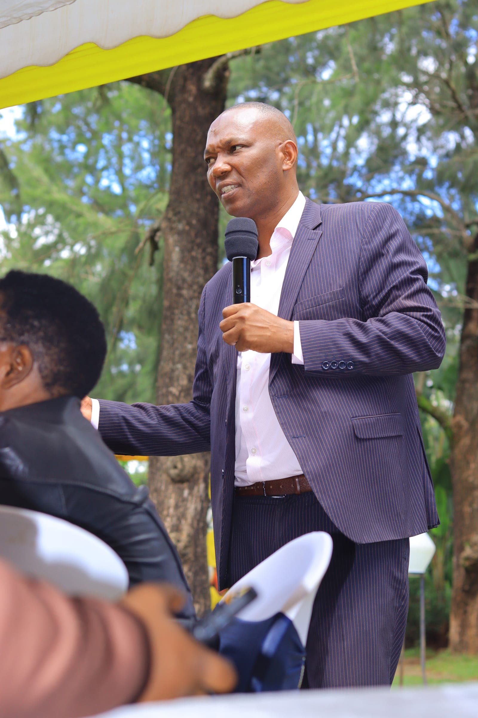 PPOK Chairman Evans Misati speaking into a microphone at an outdoor party meeting
